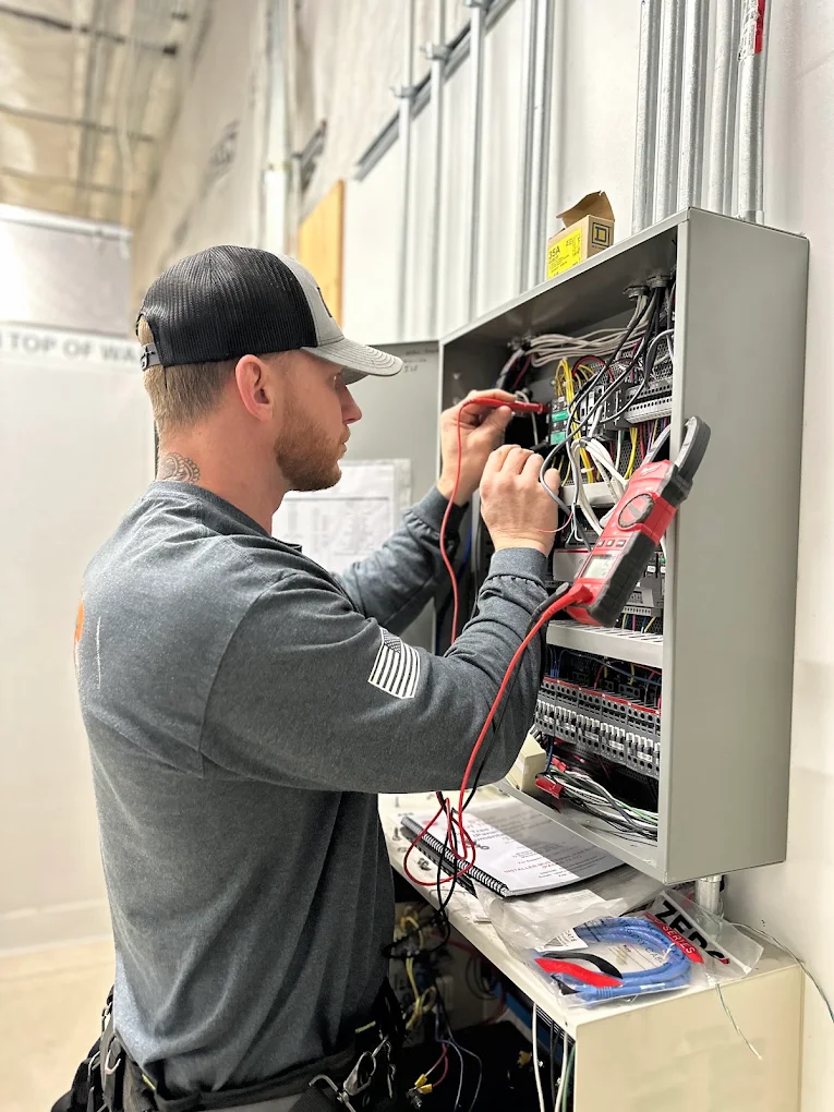Licensed Baker Electric Inc. electrician using multimeter probes for precise electrical panel testing and diagnostics.