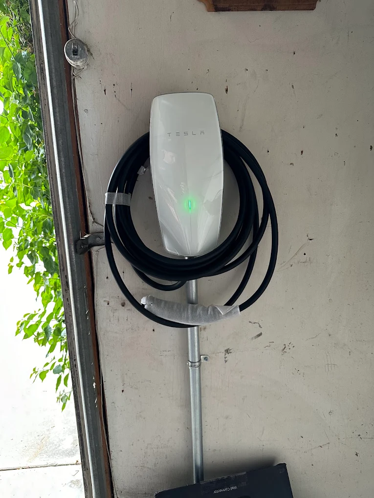 Newly installed Tesla Wall Connector EV charger powered on with active green indicator light.