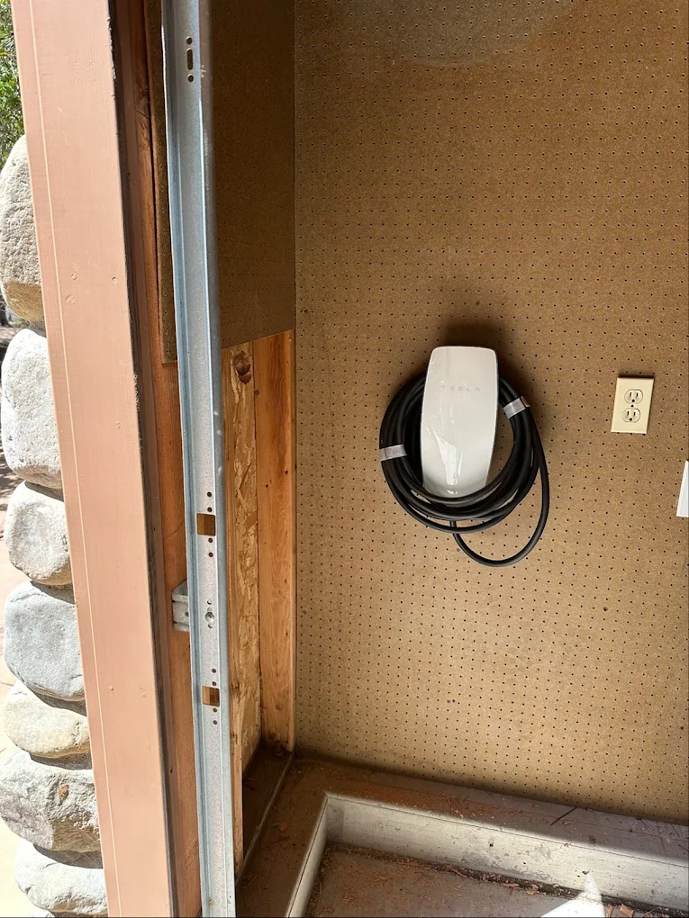 Professional wall-mounted Tesla EV Charger installation on pegboard garage wall by Baker Electric Inc.