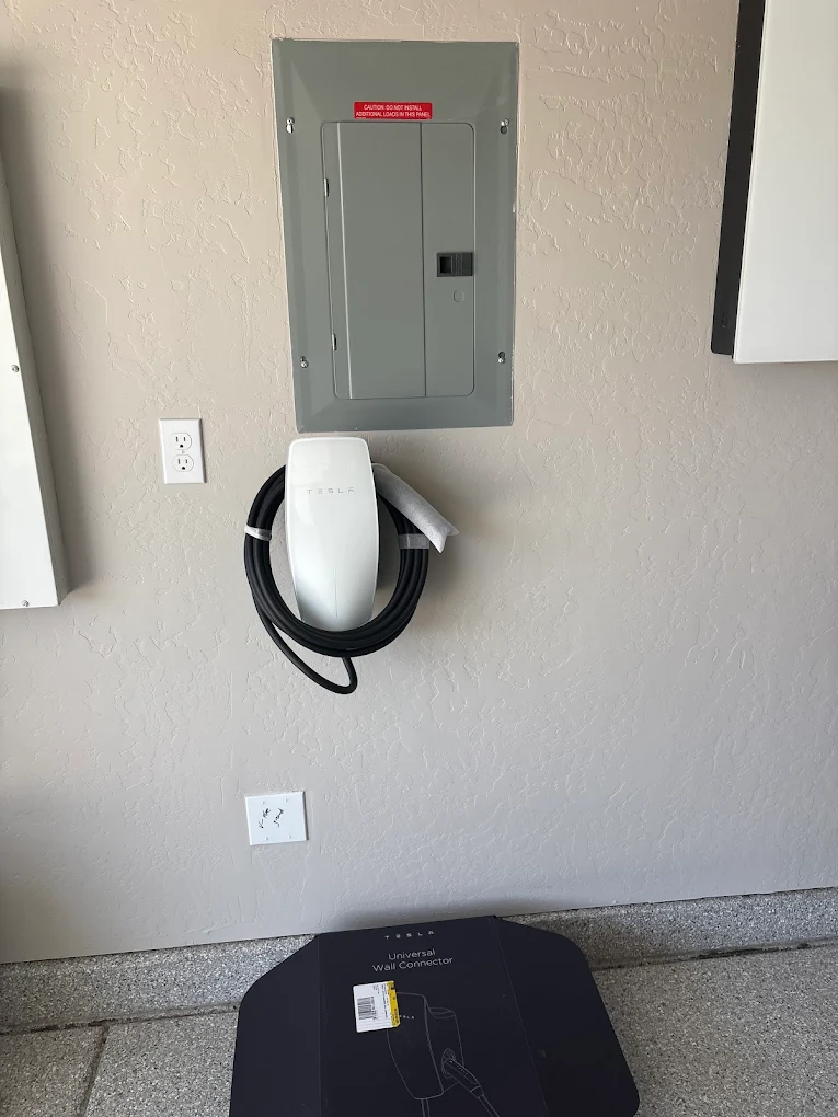 Tesla Wall Connector mounted below a main electrical breaker panel by licensed C-10 contractor.