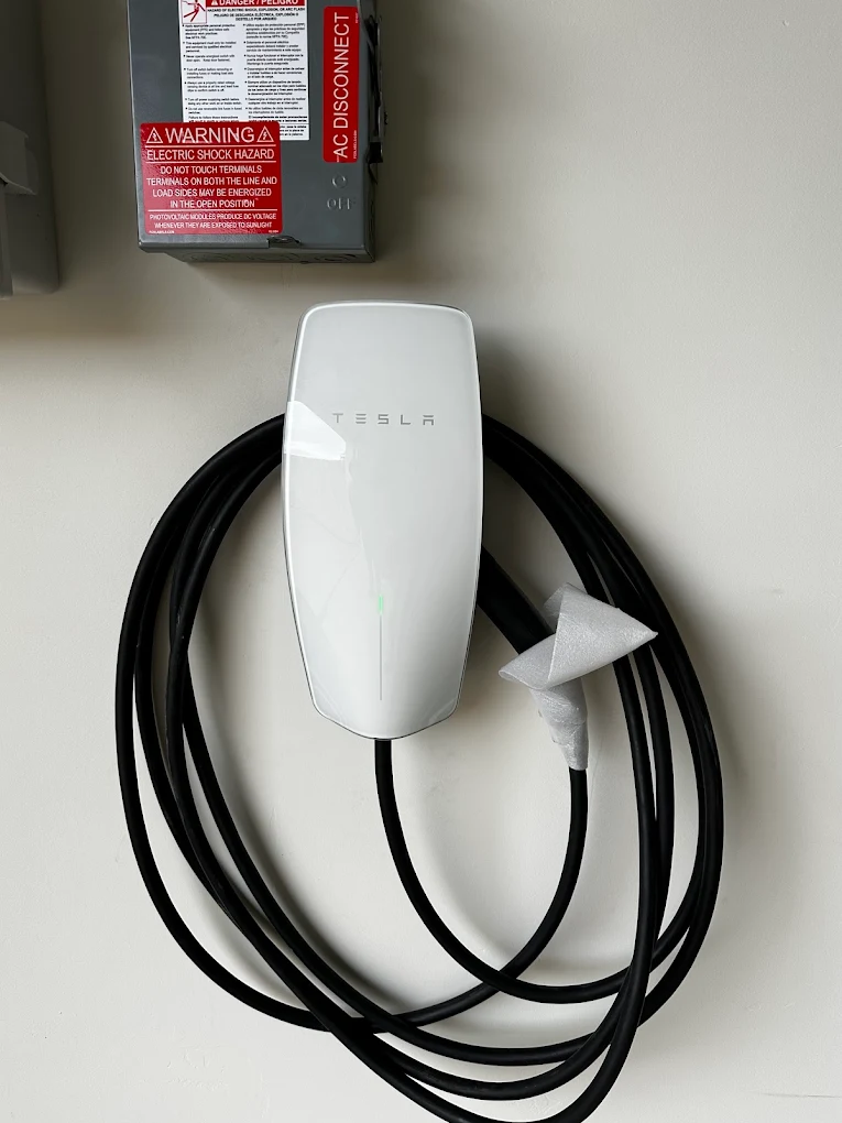 Professional wall-mounted Tesla EV Charger installation on pegboard garage wall by Baker Electric Inc.